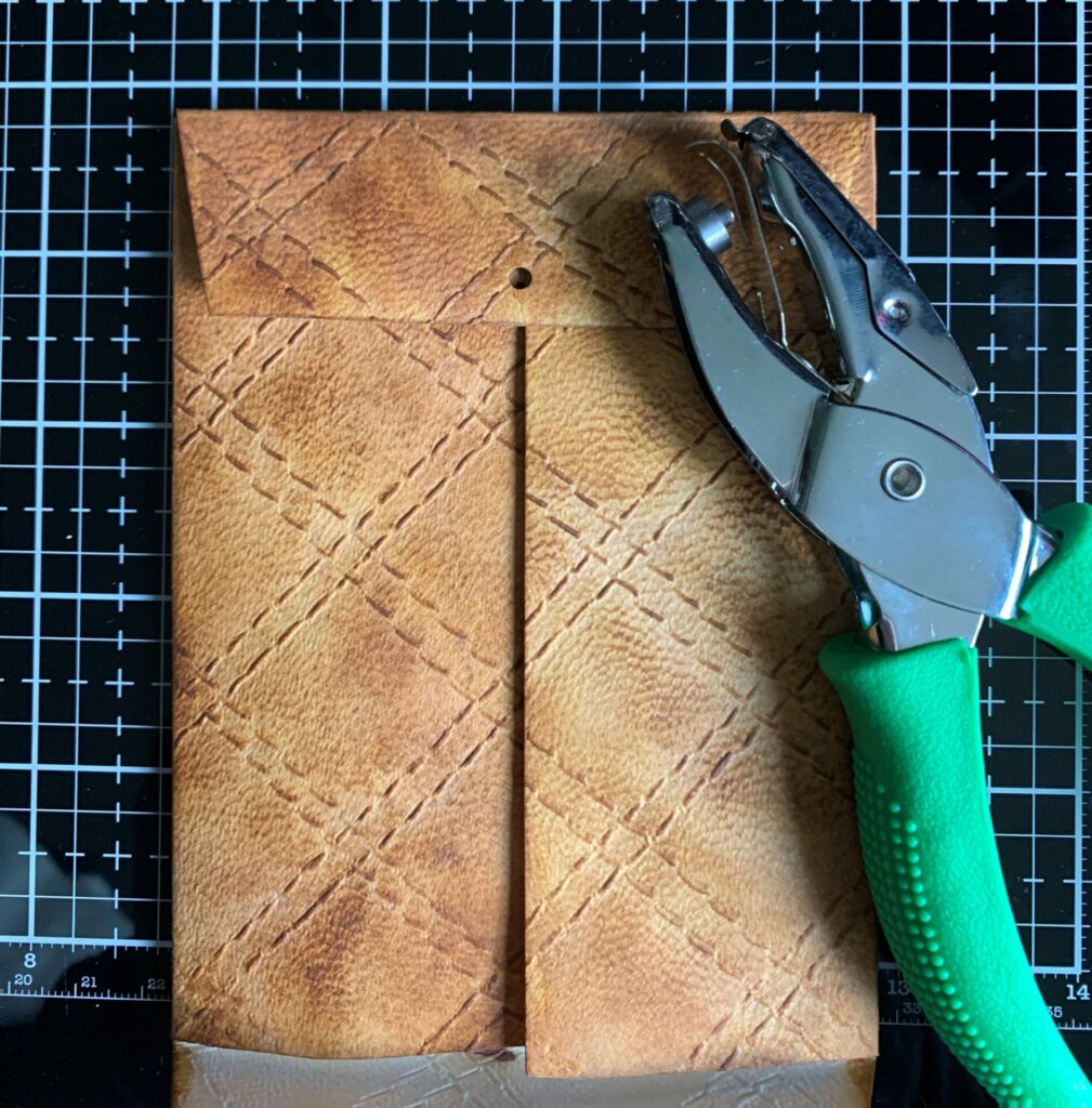 Punching the brad hole in the quilted leather envelope