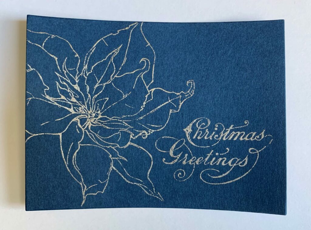 Embossing the poinsettia Christmas greetings card with silver embossing powder