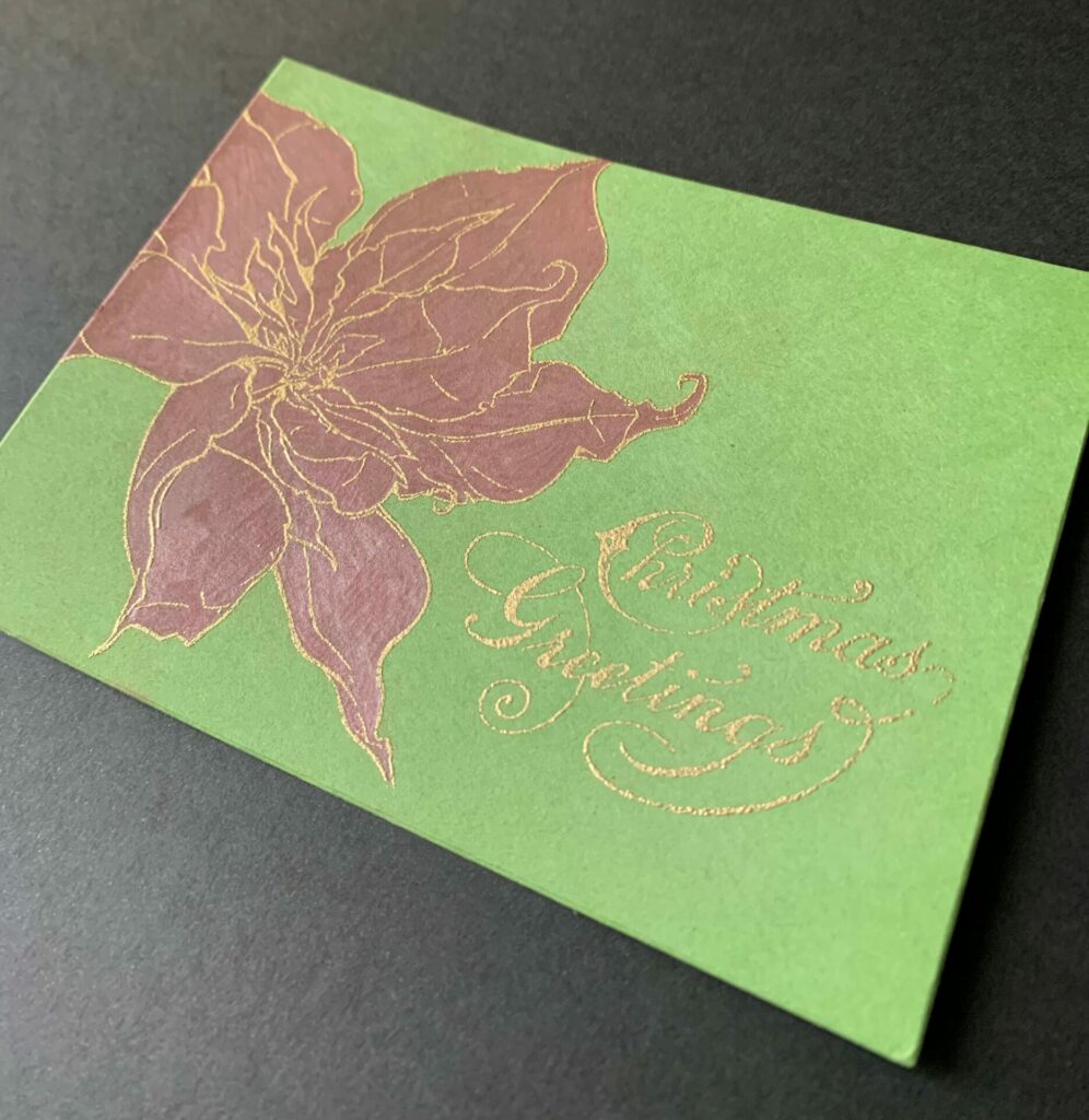Embossing the poinsettia Christmas greetings card with gold embossing powder