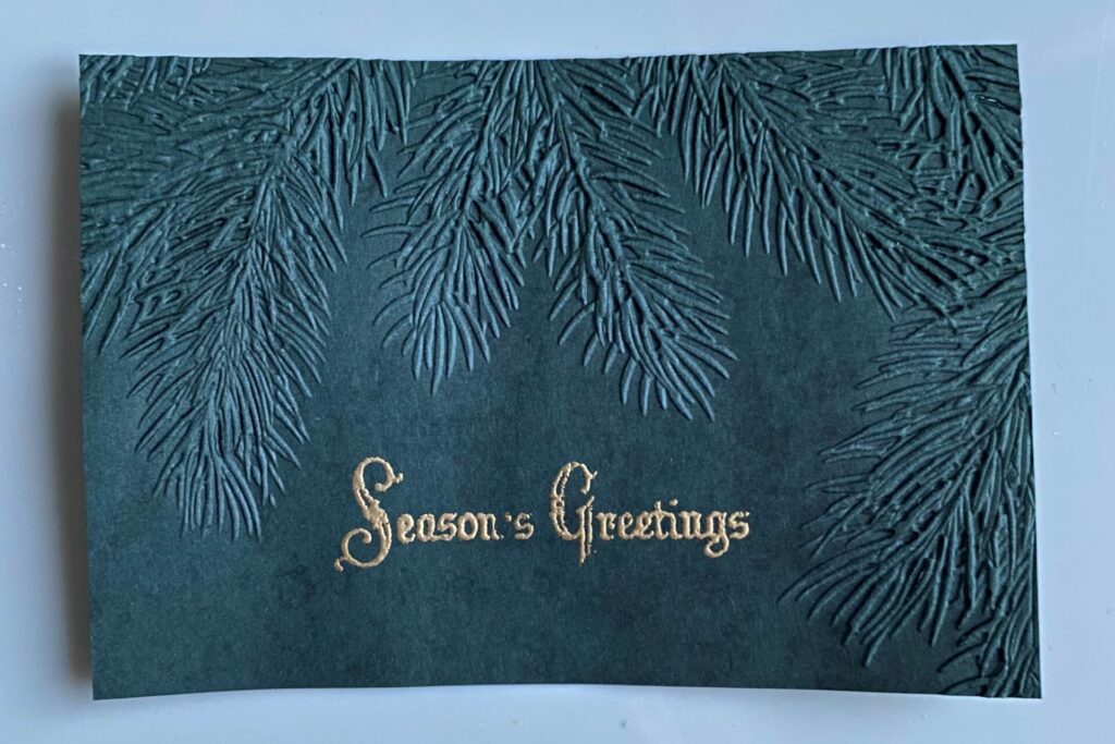 Heat embossing sentiment on the Pine Season's Greetings Card front
